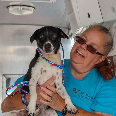 a dog held by a shelter volunteer